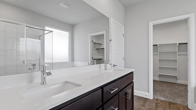 full bath with wood tiled floor, a sink, a shower stall, and a spacious closet