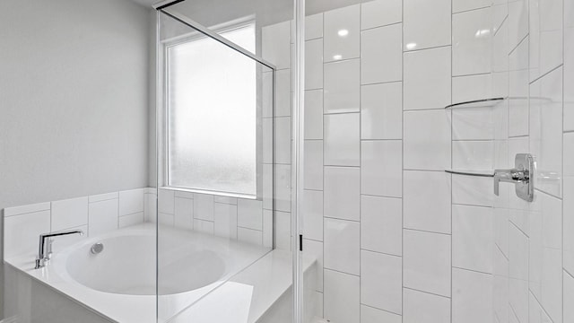 bathroom featuring a bath and tiled shower