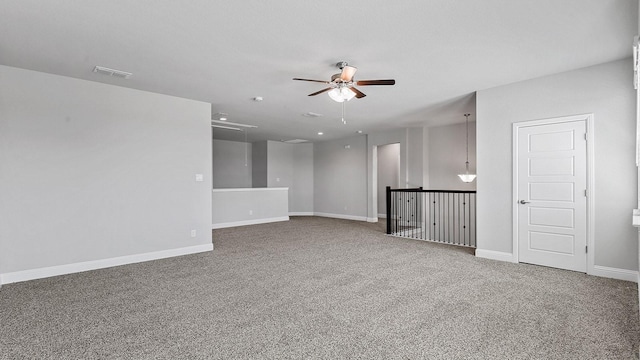 carpeted empty room with baseboards, visible vents, and a ceiling fan