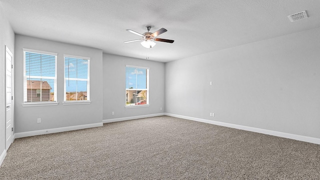 empty room featuring ceiling fan, a textured ceiling, carpet flooring, visible vents, and baseboards