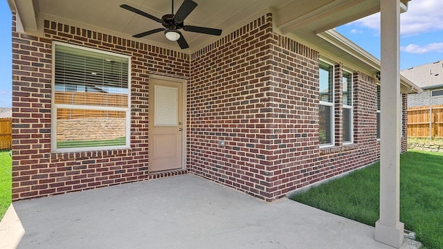 entrance to property with a patio, fence, a ceiling fan, and brick siding