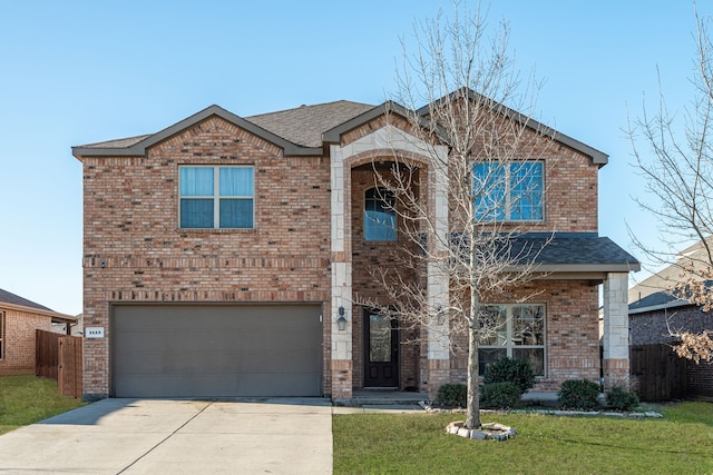 traditional-style house featuring driveway, fence, a front yard, a garage, and brick siding