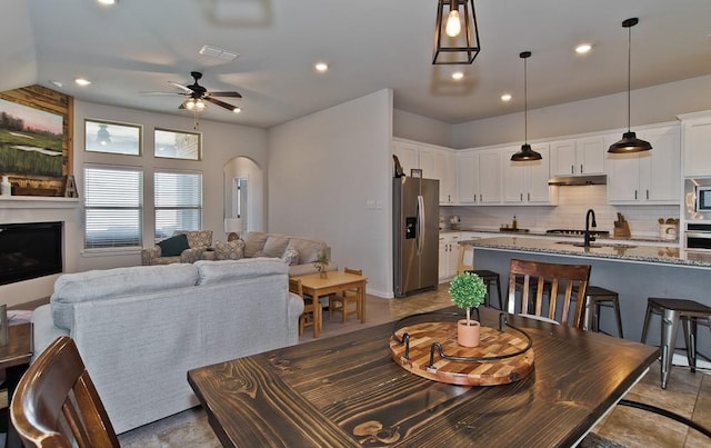 dining area with arched walkways, a fireplace, recessed lighting, visible vents, and a ceiling fan