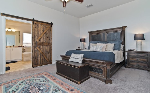 bedroom with ensuite bathroom, a barn door, light colored carpet, a ceiling fan, and visible vents