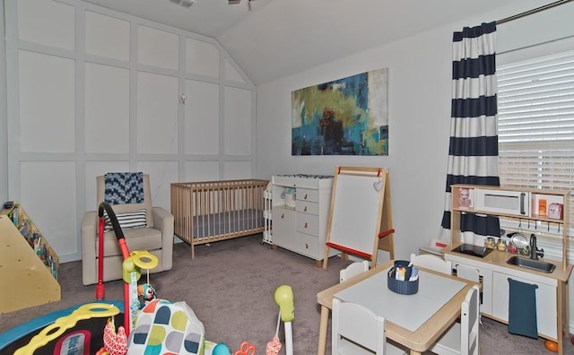 carpeted bedroom with lofted ceiling, a nursery area, a sink, and a decorative wall