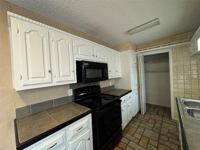 kitchen with tile counters, white cabinets, a sink, a textured ceiling, and black appliances