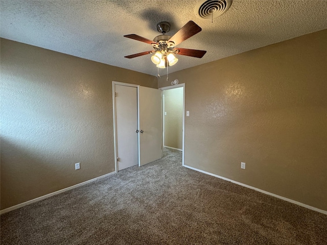 carpeted empty room featuring a textured ceiling, a textured wall, visible vents, and baseboards