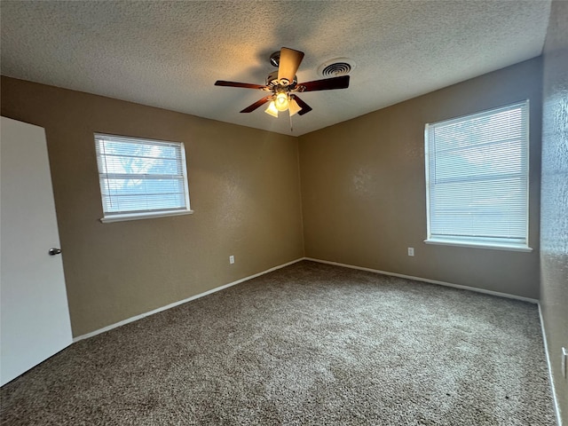 empty room featuring ceiling fan, a textured ceiling, carpet flooring, visible vents, and baseboards