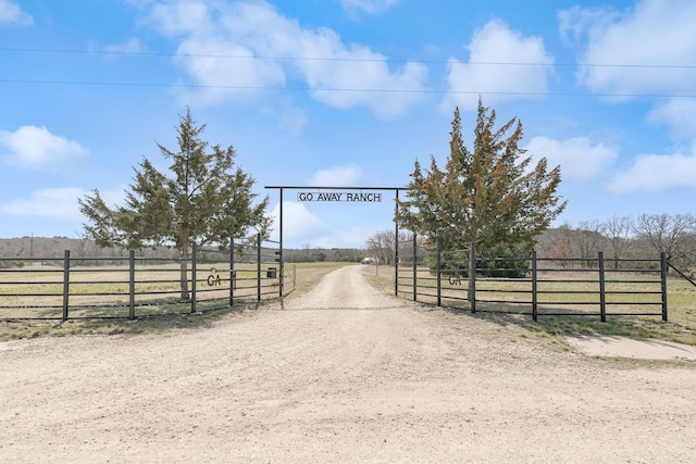 view of street featuring dirt driveway, a rural view, a gate, and a gated entry