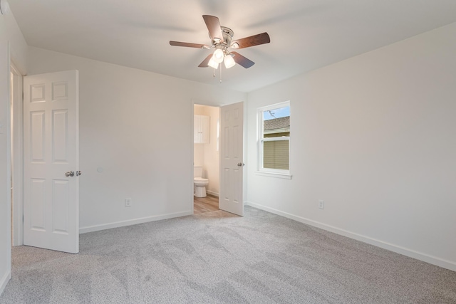 unfurnished bedroom with light carpet, connected bathroom, baseboards, and ceiling fan