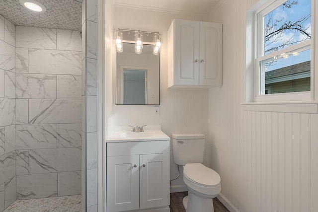 full bathroom with baseboards, a tile shower, vanity, and toilet