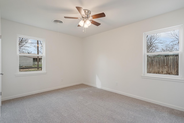 carpeted empty room with a ceiling fan, visible vents, and baseboards