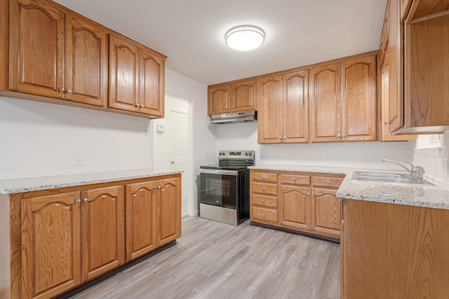 kitchen featuring light stone counters, electric stove, light wood finished floors, a sink, and under cabinet range hood