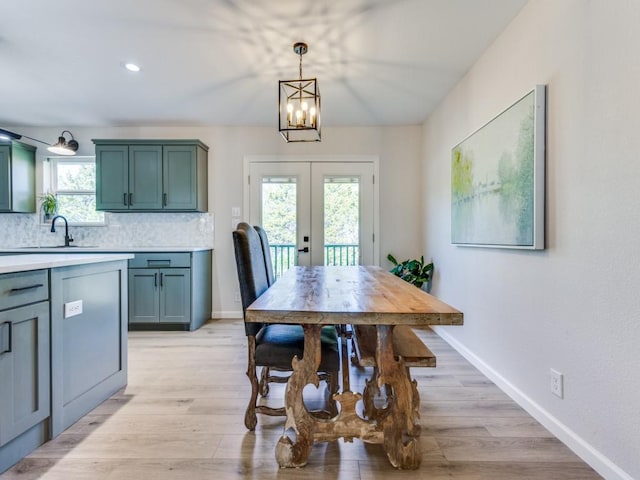 dining area with light wood-style flooring, baseboards, recessed lighting, an inviting chandelier, and french doors