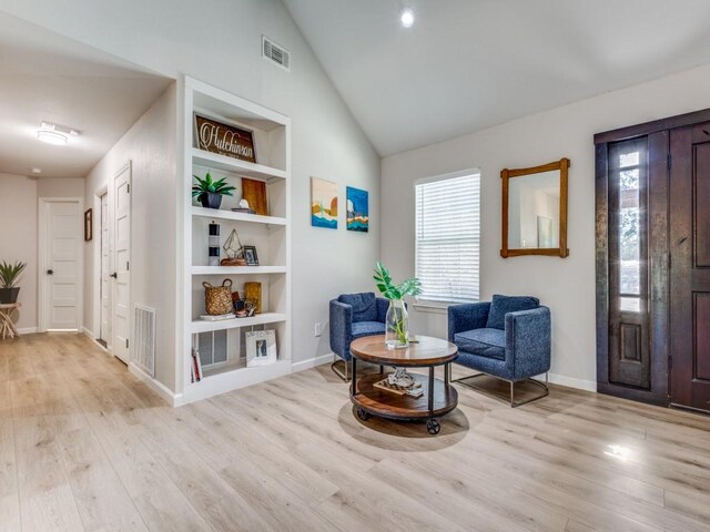 living area with visible vents, light wood-style flooring, and built in shelves
