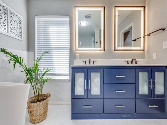 full bathroom featuring marble finish floor, a sink, double vanity, and a soaking tub