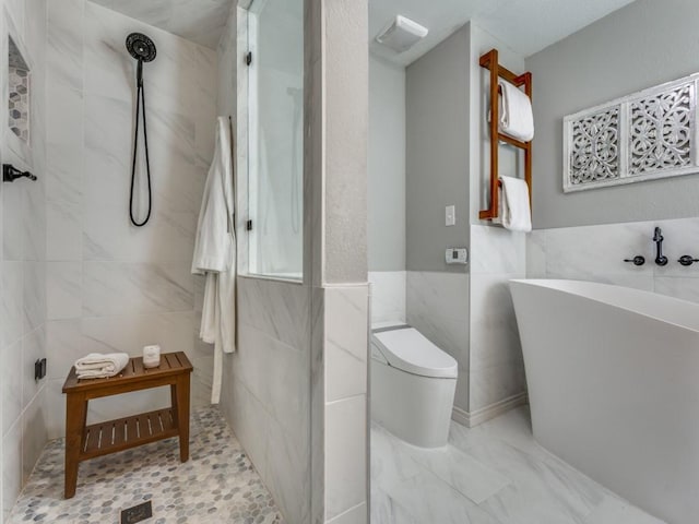 full bath with tile walls, toilet, a walk in shower, and a freestanding bath