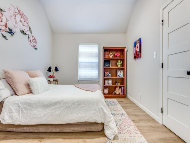 bedroom featuring baseboards, lofted ceiling, and light wood-type flooring