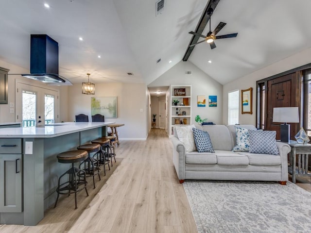 living area featuring visible vents, baseboards, lofted ceiling with beams, french doors, and light wood-type flooring