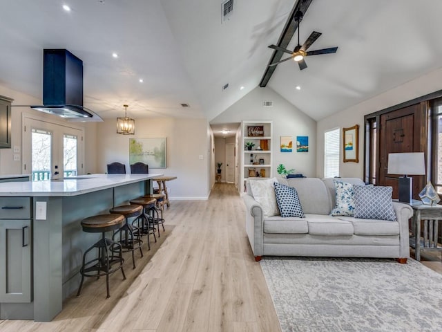 living area featuring lofted ceiling with beams, baseboards, ceiling fan, light wood-style flooring, and visible vents