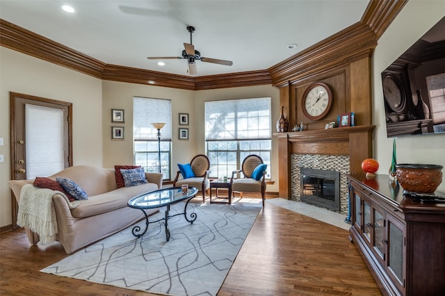 living area with a fireplace, crown molding, recessed lighting, ceiling fan, and wood finished floors