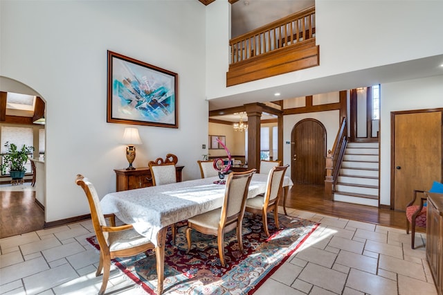 dining room with arched walkways, a notable chandelier, a towering ceiling, baseboards, and stairway