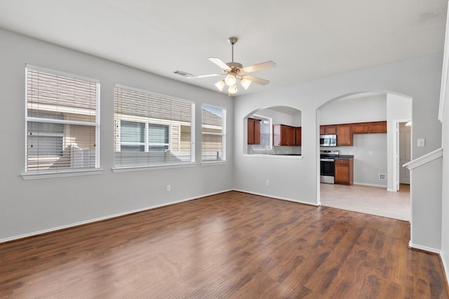 empty room featuring baseboards, ceiling fan, visible vents, and wood finished floors