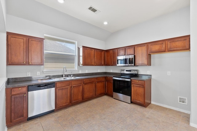 kitchen featuring brown cabinets, dark countertops, visible vents, appliances with stainless steel finishes, and a sink