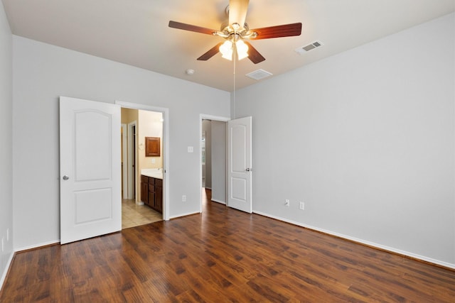 unfurnished bedroom featuring baseboards, visible vents, ensuite bath, and wood finished floors