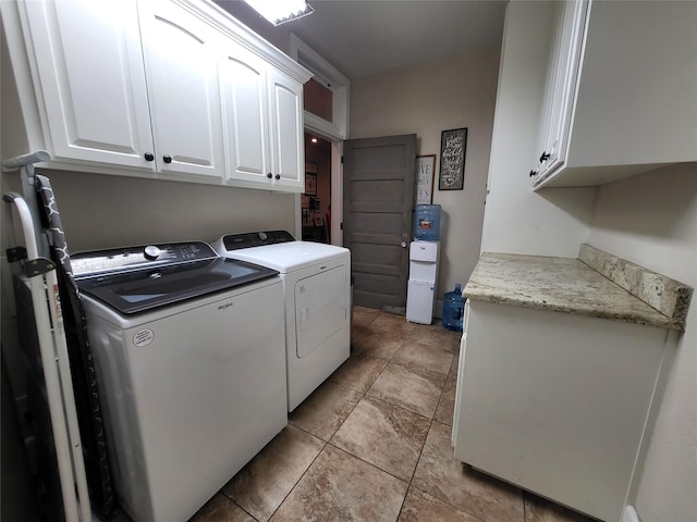 laundry area with washing machine and dryer, cabinet space, and light tile patterned floors