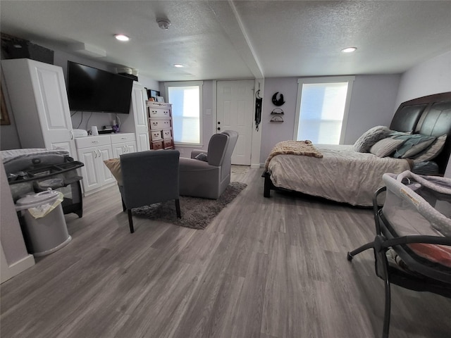 bedroom featuring light wood-type flooring, multiple windows, a textured ceiling, and recessed lighting