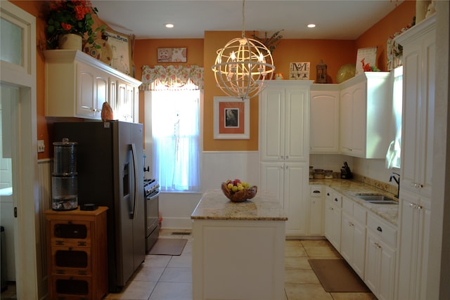 kitchen with light stone counters, a kitchen island, a sink, stainless steel fridge with ice dispenser, and gas stove