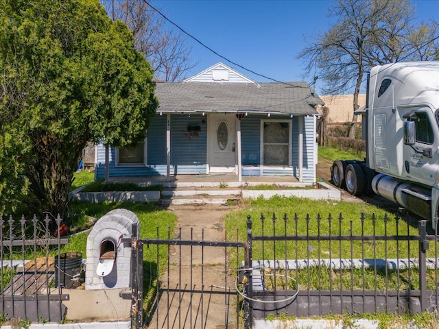 bungalow with a front lawn, a fenced front yard, a porch, roof with shingles, and a gate