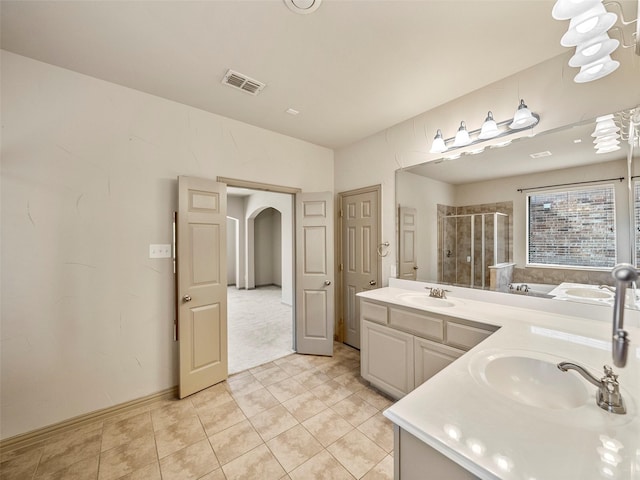 bathroom featuring visible vents, a sink, a shower stall, and double vanity