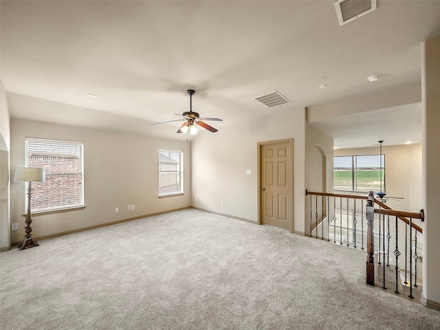 empty room with carpet floors, a healthy amount of sunlight, and visible vents