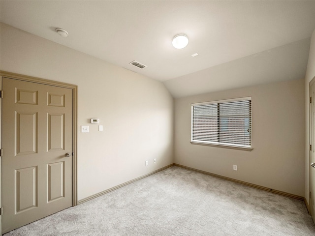 carpeted empty room featuring baseboards, visible vents, and vaulted ceiling