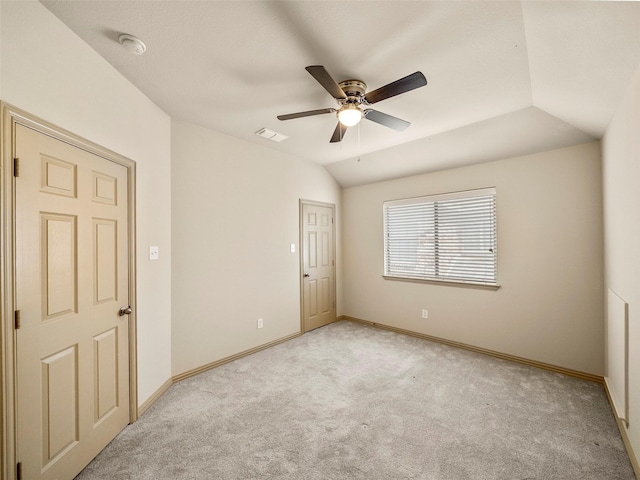 empty room featuring lofted ceiling, baseboards, visible vents, and light colored carpet