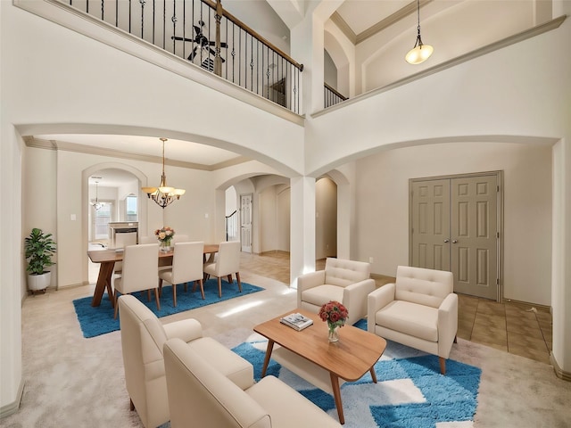 living area with ornamental molding, arched walkways, light colored carpet, and an inviting chandelier