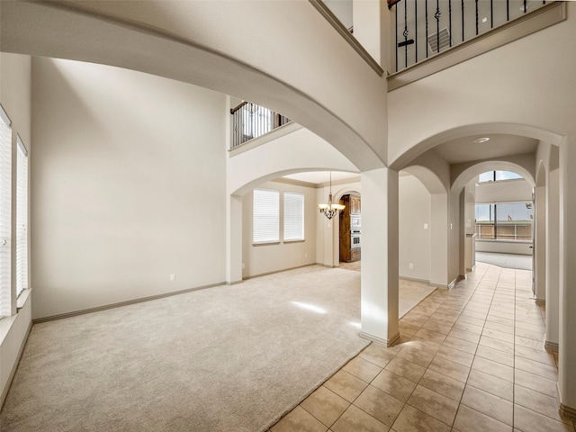 interior space with light carpet, a wealth of natural light, arched walkways, and a towering ceiling