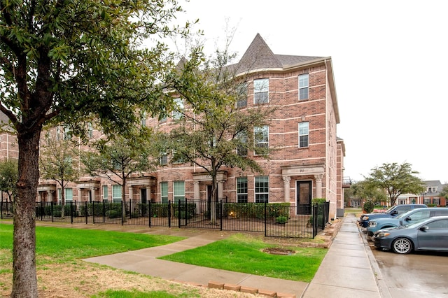 multi unit property featuring brick siding, a fenced front yard, and a front lawn