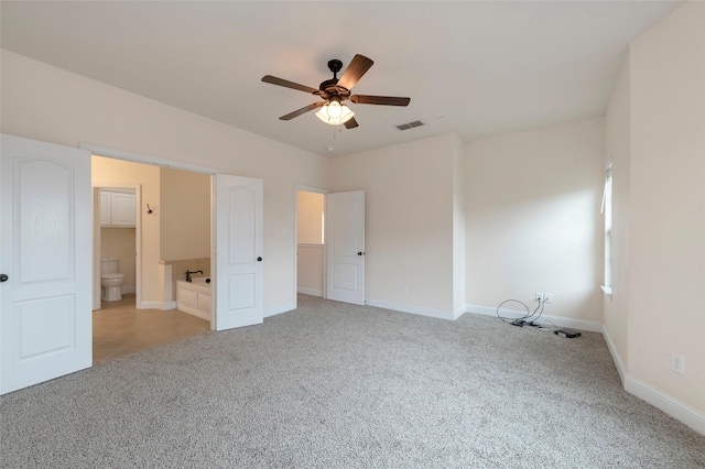 unfurnished bedroom featuring ensuite bath, baseboards, visible vents, and light colored carpet