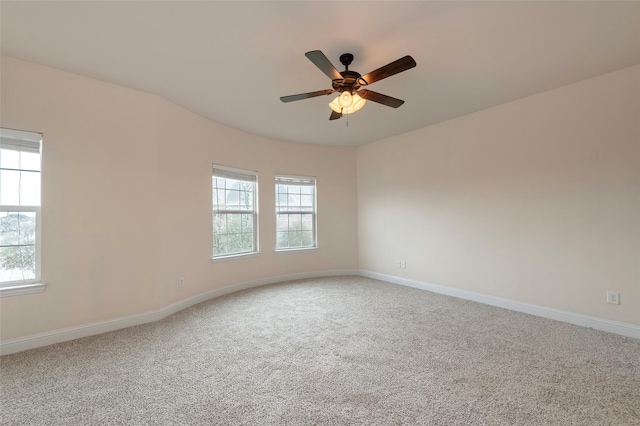 carpeted spare room with a ceiling fan, a wealth of natural light, and baseboards