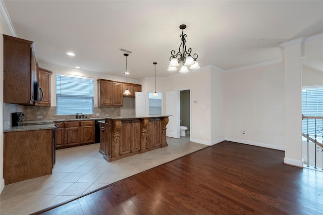 kitchen featuring a healthy amount of sunlight, a kitchen island, light wood finished floors, and decorative backsplash