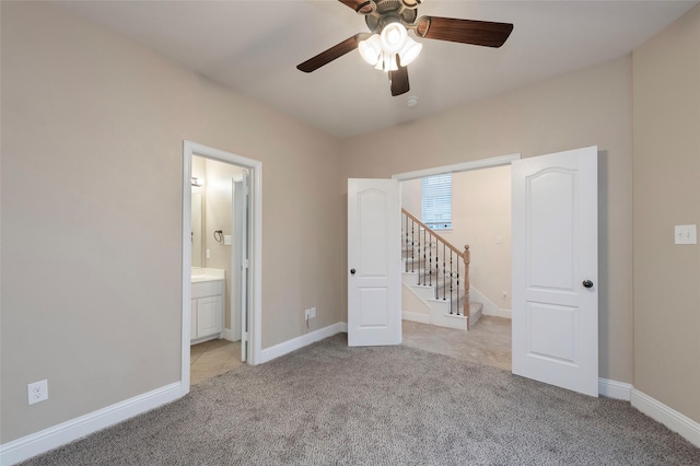 unfurnished bedroom with light carpet, ceiling fan, ensuite bath, and baseboards