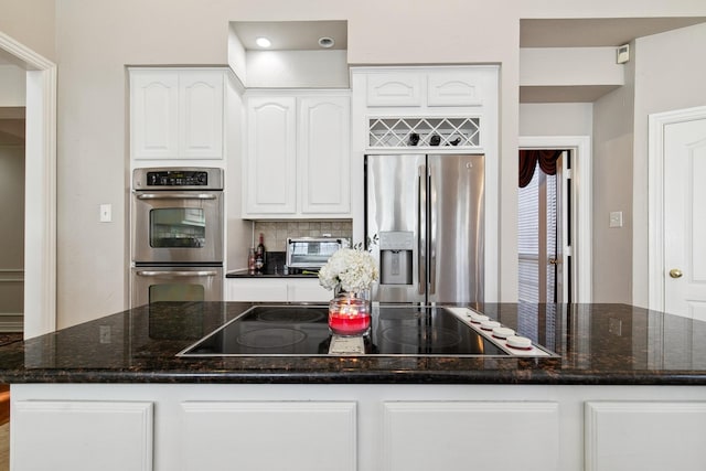 kitchen featuring dark stone counters, stainless steel appliances, a kitchen island, and white cabinetry