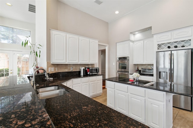 kitchen featuring stainless steel appliances, dark stone countertops, a sink, and visible vents