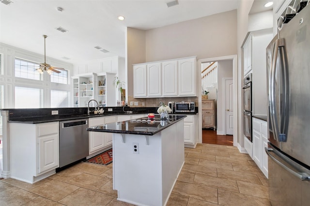 kitchen featuring visible vents, white cabinets, appliances with stainless steel finishes, a center island, and a peninsula