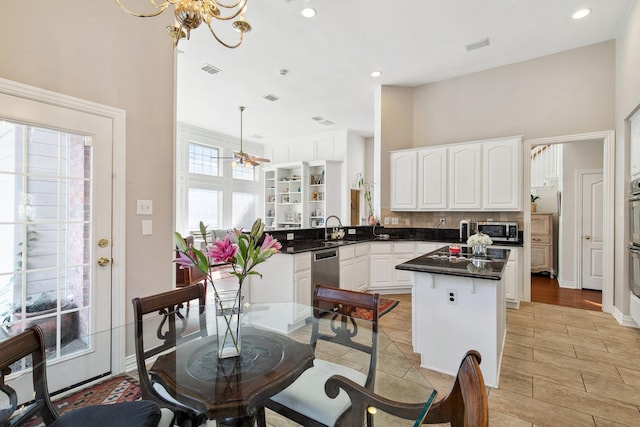 kitchen featuring decorative backsplash, dark countertops, a kitchen island, stainless steel appliances, and white cabinetry