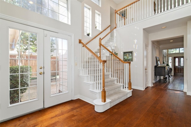 foyer featuring wood-type flooring, a high ceiling, and french doors