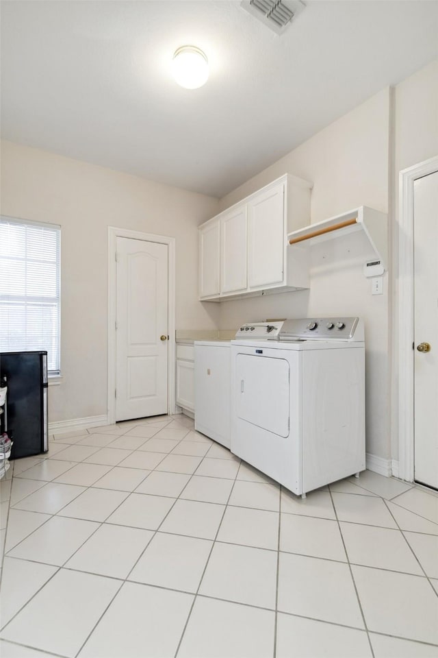 washroom featuring separate washer and dryer, light tile patterned flooring, cabinet space, and visible vents